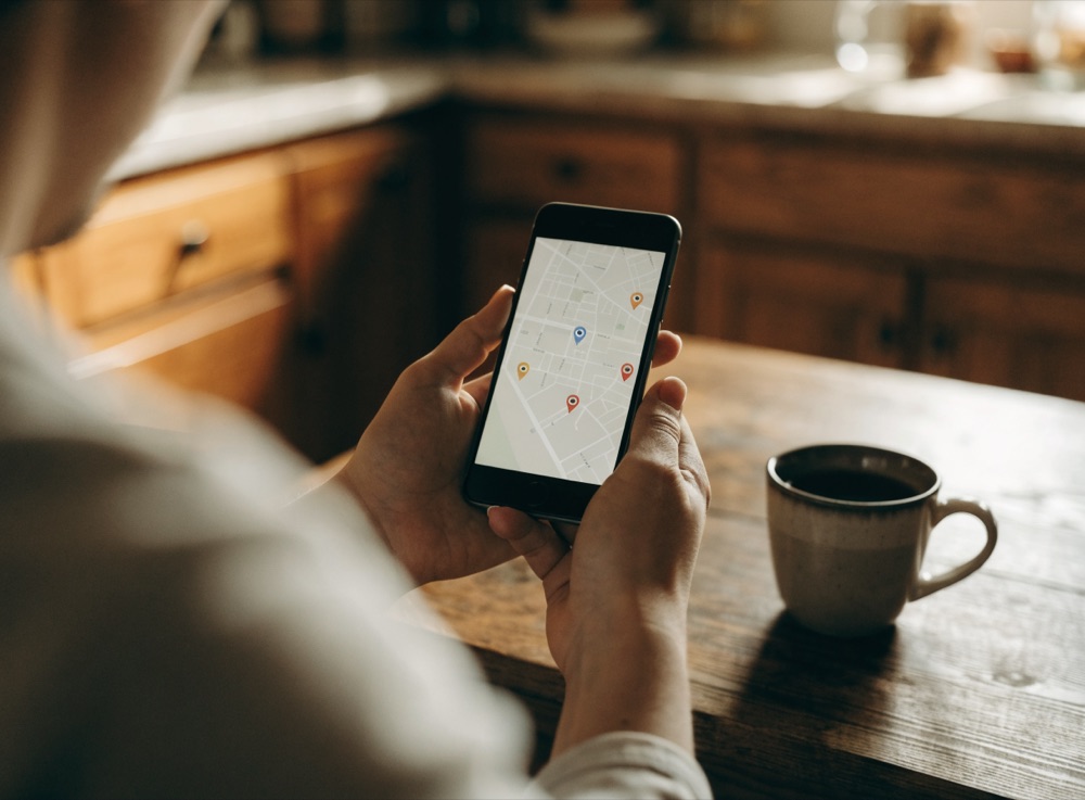 Homeowner searching a local map on a smartphone at a kitchen table
